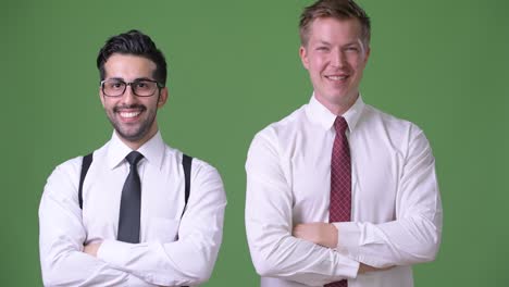two young multi-ethnic businessmen working together against green background