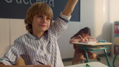 child raising hand at lesson in auditorium. smart student answering question