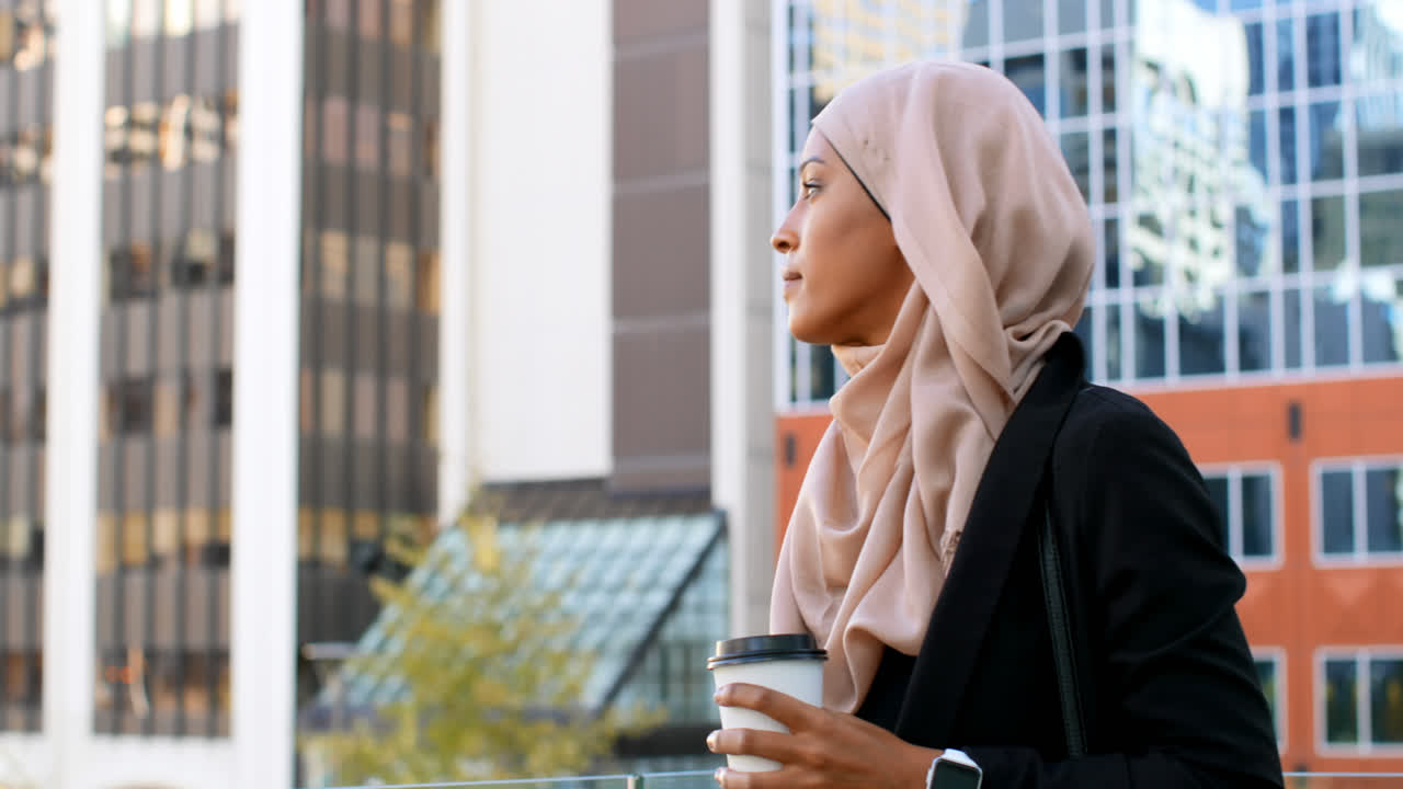 Side view of young Asian woman in hijab standing in the city 4k