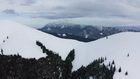 Snow-covered-Piatra-Craiului-Mountains-seen-from-Iezer-Papusa,-Romania,-aerial-view