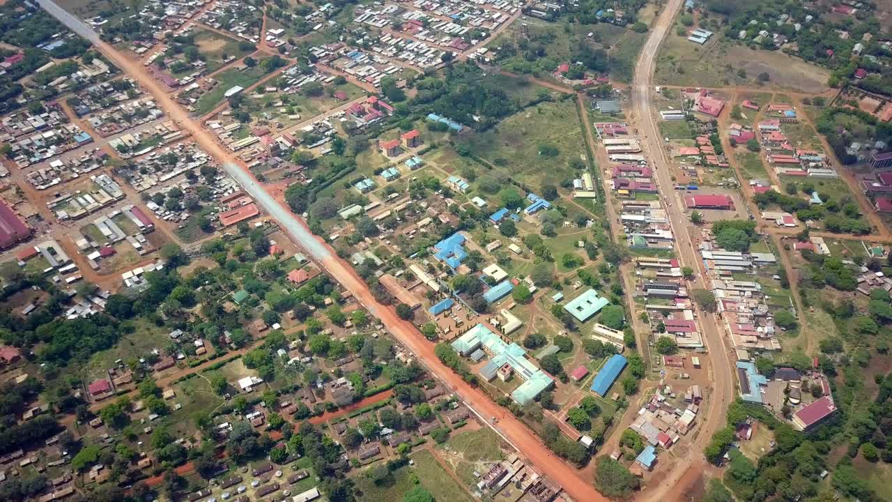 Aerial view showcasing the urban landscape of Moroto, Uganda, featuring roads, blue roofs buildings, and green spaces, highlighting town's layout infrastructure development, drone establishing shot