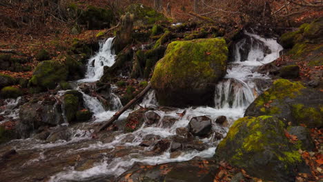 Zeitlupenaufnahmen-Eines-Doppelten-Wasserfalls,-Der-Im-Spätherbst-Im-Chugach-State-Park-In-Der-Nähe-Von-Anchorage,-Alaska,-Um-Moosbedeckte-Felsbrocken-Fließt