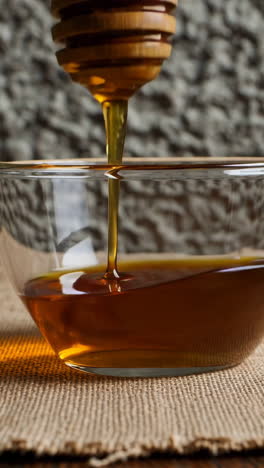honey pouring into bowl with wooden dipper