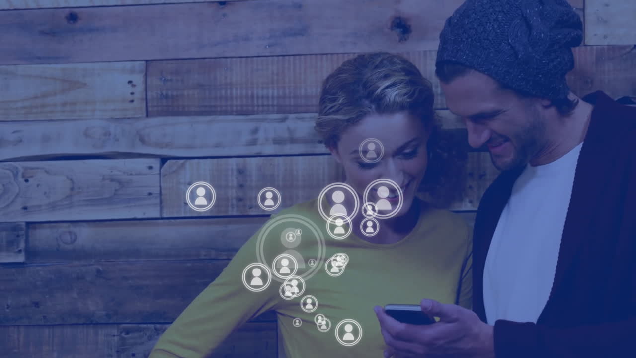 animación de iconos de las redes sociales sobre una pareja caucásica que usa un teléfono inteligente