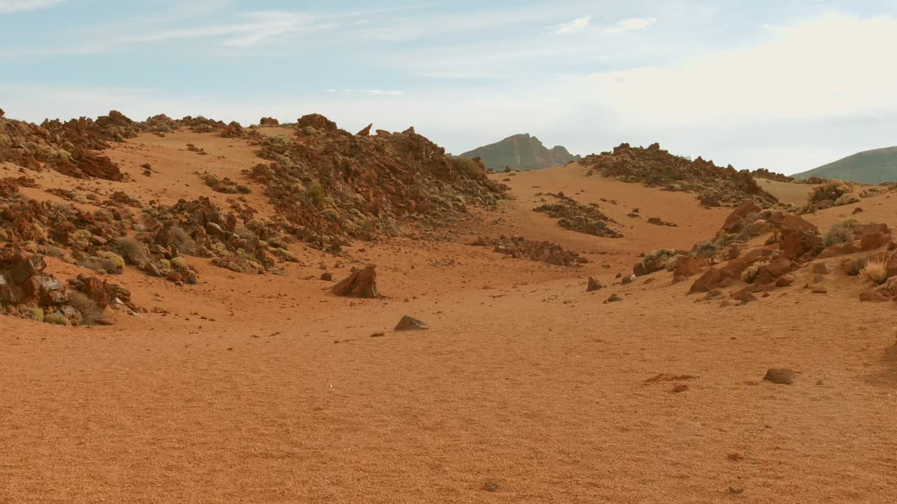 Panning shot across a stark desert region in Tenerife, Canary Islands, Spain, evoking a Mars-like atmosphere. Showcases the unique volcanic terrain and arid beauty of this European landscape.