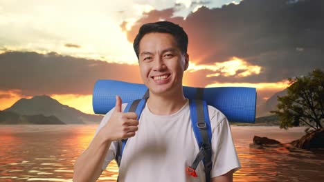 close up of asian male hiker with mountaineering backpack smiling and showing thumbs up gesture to camera at a lake