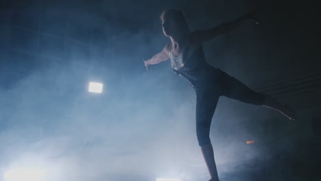 in slow motion in the smoke, a girl athlete stands with her arms raised after performing exercises. welcome gesture with your hands.