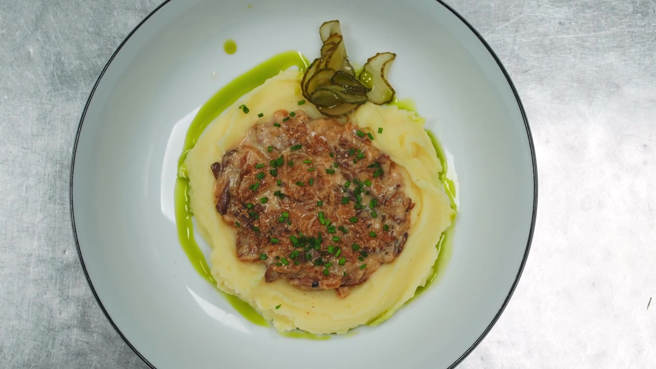 Chef che guarnisce un piatto gourmet con olio verde.