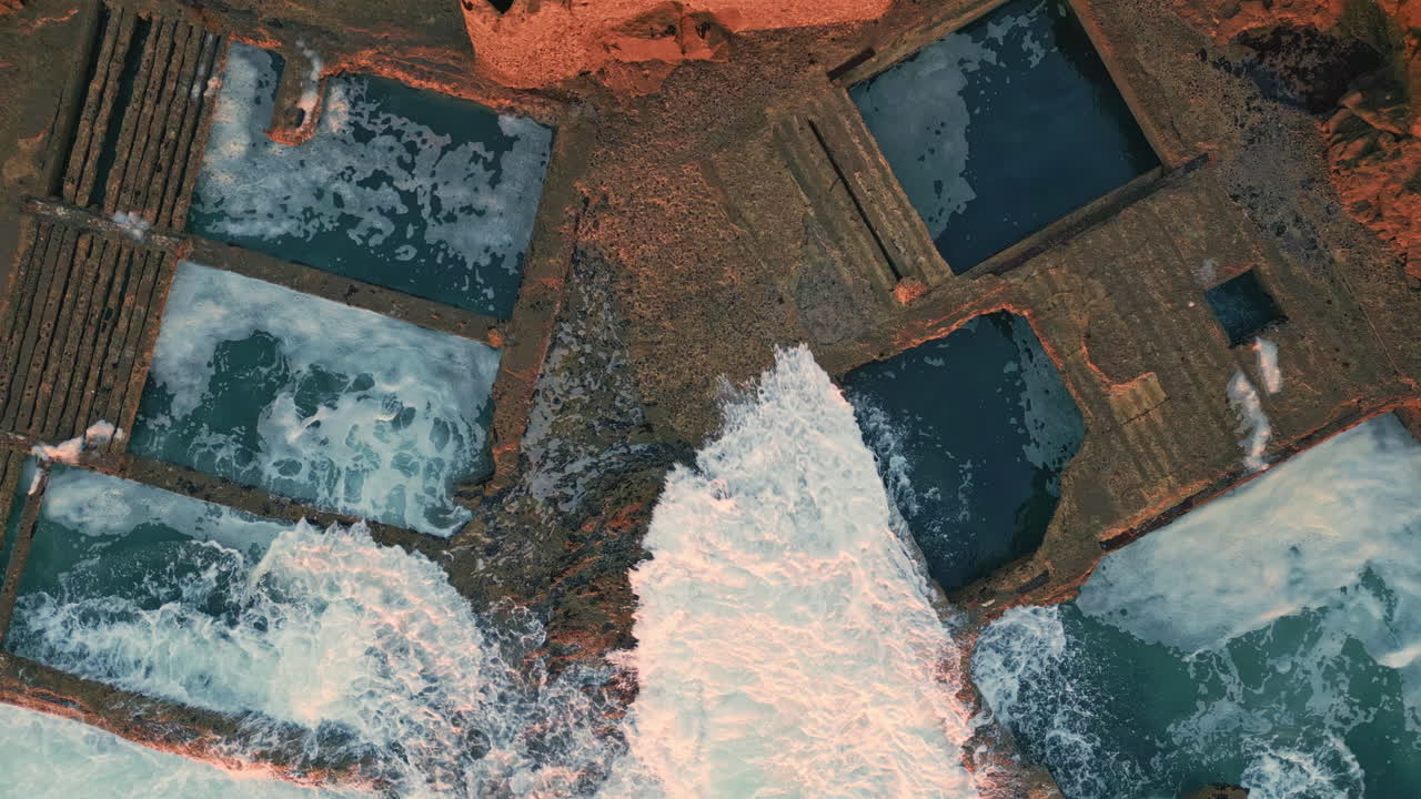 Rough coastal stones washed by stormy foamy ocean top view. Beautiful waves