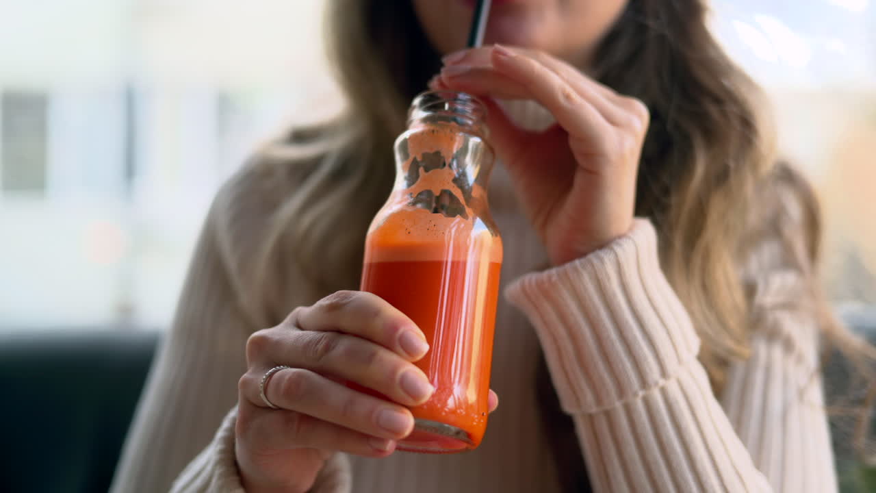 Mujer bebiendo zumo de zanahoria en una botella de cristal con una pajita negra