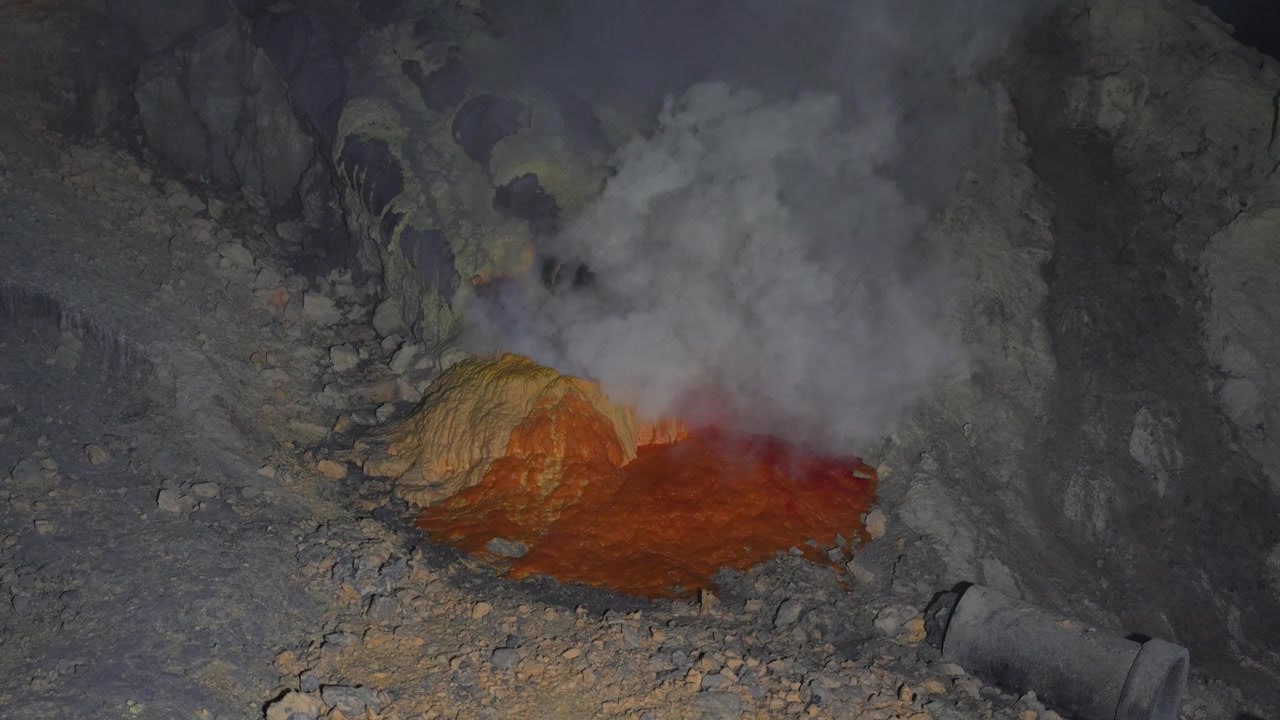 Sulfur condensation pipes release dense volcanic fumes inside Kawah Ijen's active mine in a static close shot.