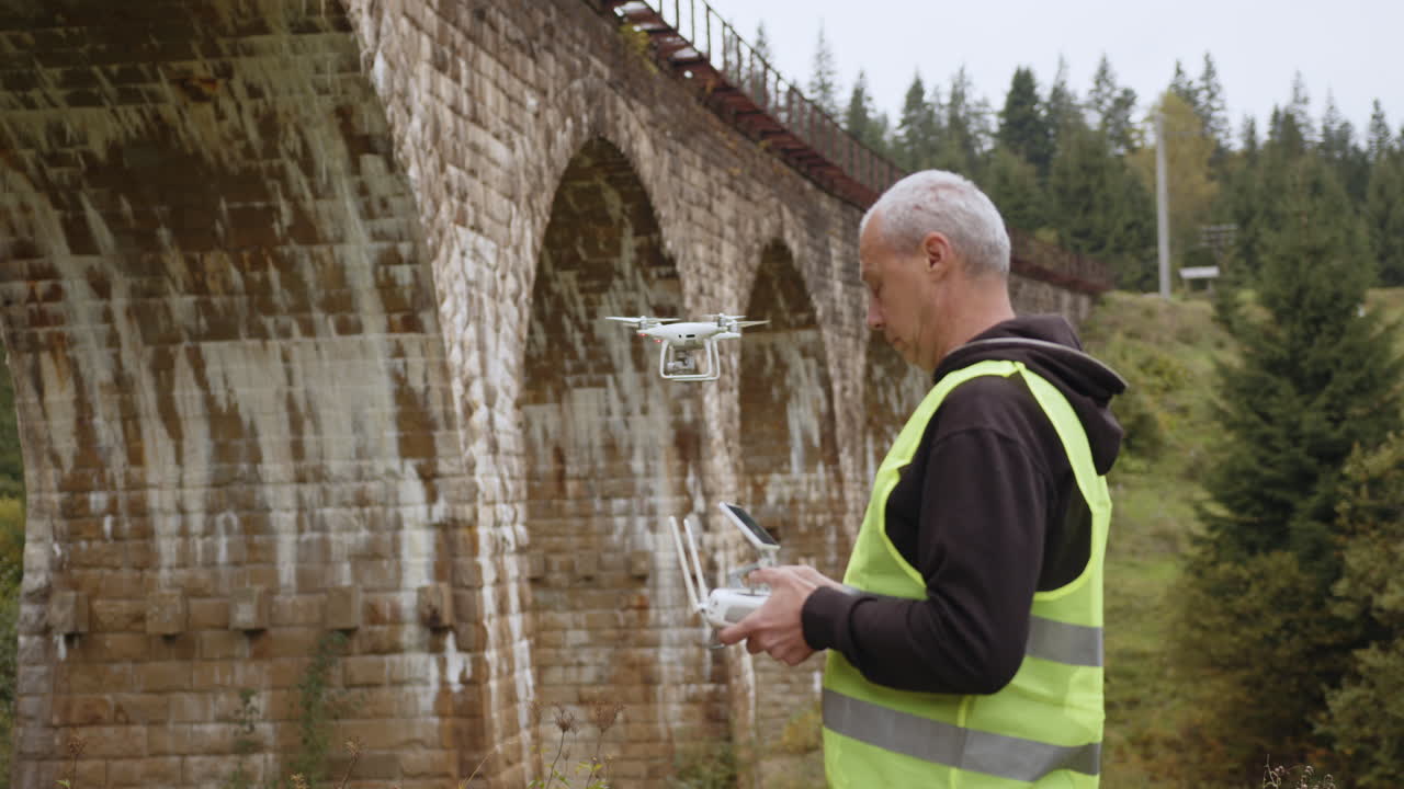 hombre operando un dron cerca de un viejo puente ferroviario