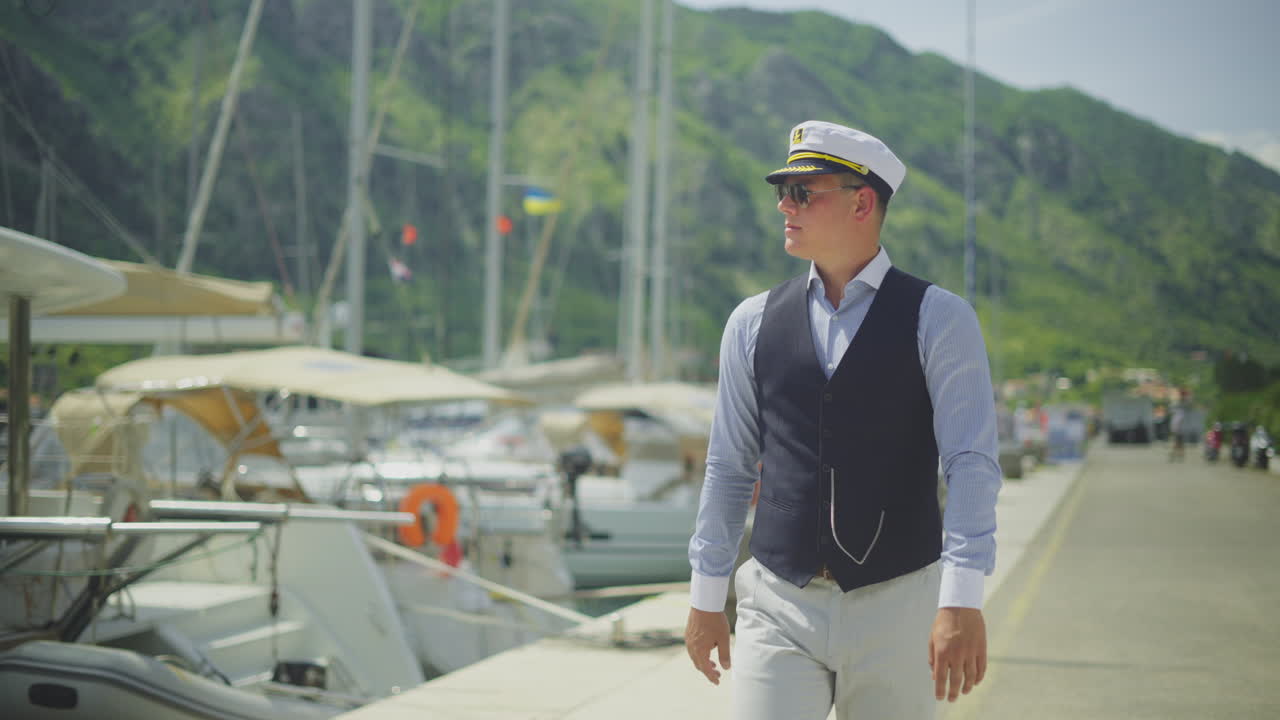 Man in Captain's Uniform on Dock by Yachts