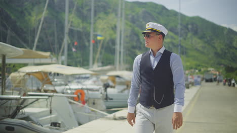 man in captain's uniform on dock by yachts