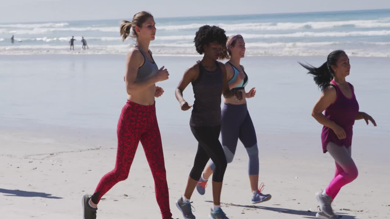 Multi-ethnic group of women running on the beach and blue sky background