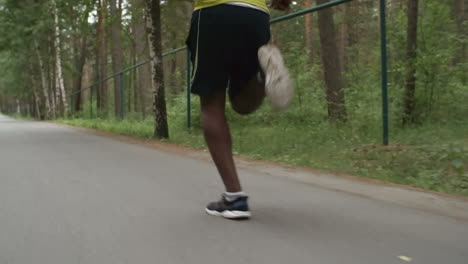 camera focuses on feet of man running in the forest