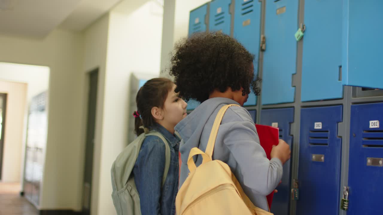 Diverse teen girls entering left at lockers leader opening blue locker pulling red binder for class