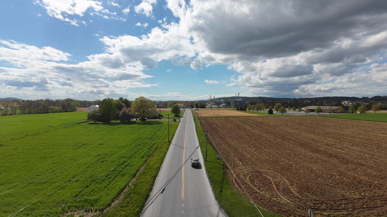 fpv 드론은 조용한 시골 도로와 농장 위를 날아갑니다.