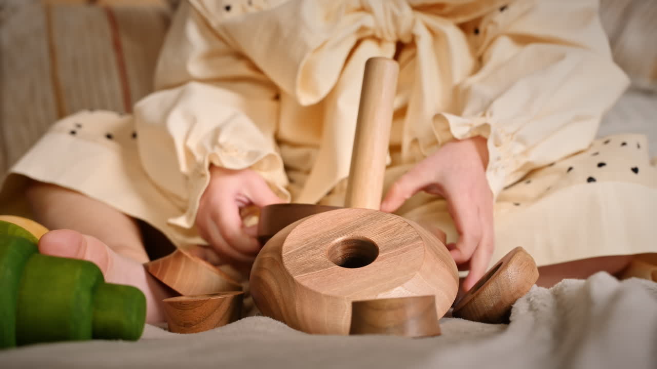 Little girl's hands playing with a wooden stacking jug. Ecological and sustainability concept