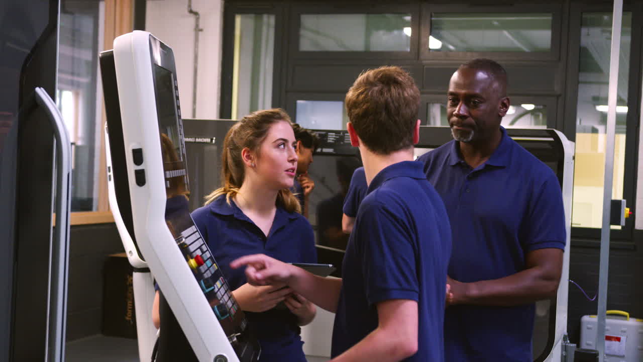 엔지니어가 견습생에게 cnc 도구 제조 기계를 사용하는 방법을 보여줍니다.