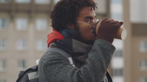 young man drinking coffee outdoors in the city