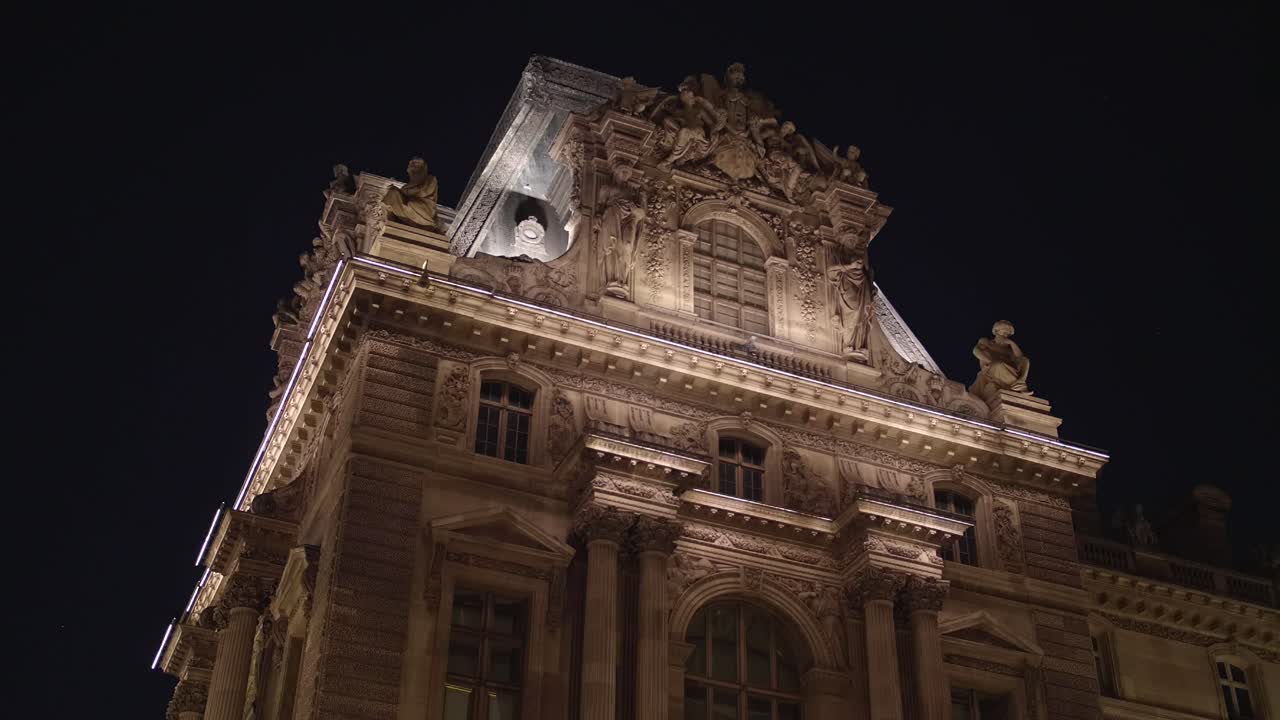 Historic building facade Musée du Louvre. Glide shot. Paris tourism attraction famous landmark. Romantic honeymoon travel destination. Glide shot in 4k. Close up view of Louvre building at night time.