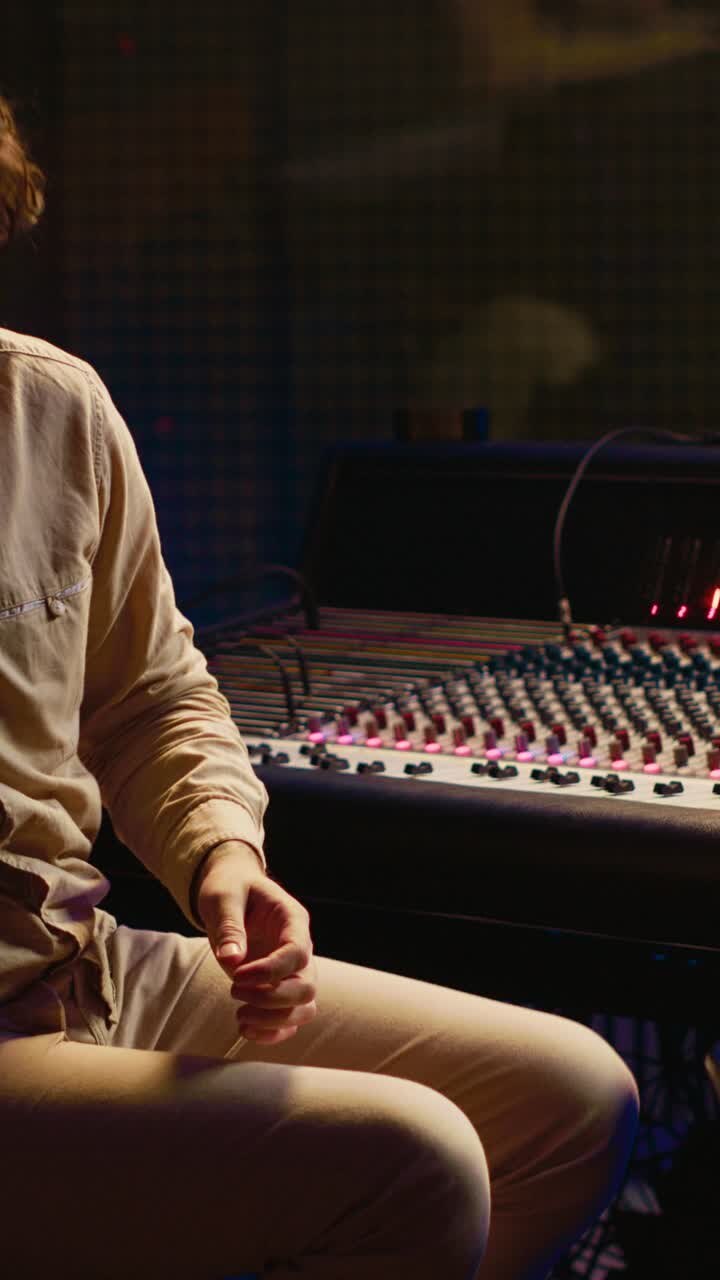 Man Playing Acoustic Guitar and Adjusting Sound Mixer in Studio