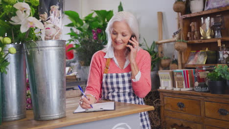 propietaria de una floristería con clipboard tomando pedidos por teléfono