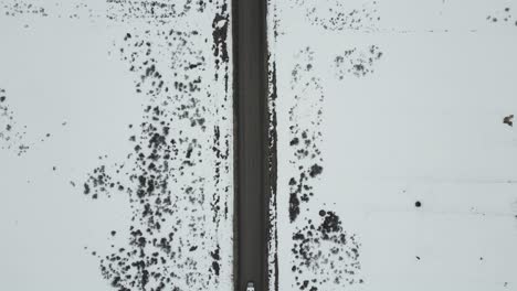 high above road in winter with white truck crossing, aerial top down view