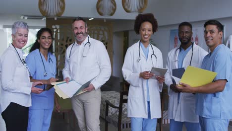 portrait of diverse male and female doctors standing in hospital corridor smiling to camera