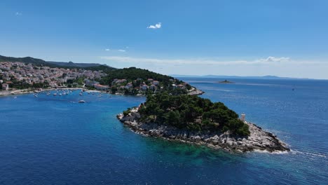 aerial: hvar old town during the day with yachts, port and adriatic sea in croatia, orbit drone shot