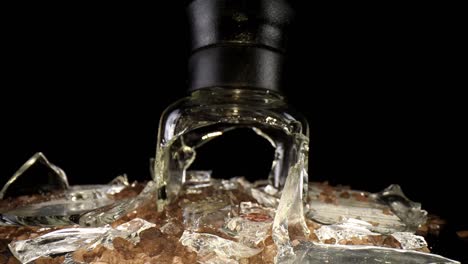 Slowly-pulling-away-from-a-broken-sea-salt-grinder,-top-portion-standing-upright,-wide-angle-macro-view-of-the-broken-glass-and-salt-intermixed---salt-is-mesquite-flavored-hence-the-darker-color