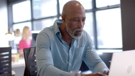 african american businessman using laptop in office with copy space