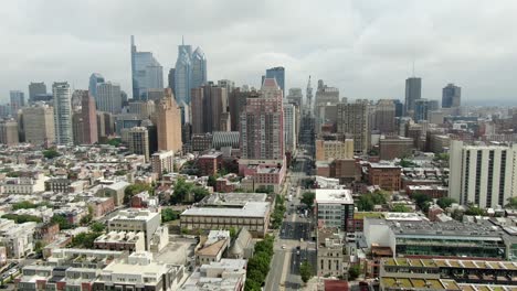 aerial pullback shot reveals philadelphia skyline, looking north on broad street toward city hall on cloudy summer day