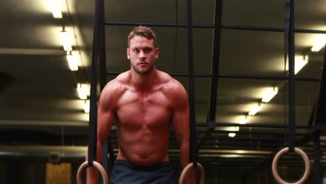 fit man using gymnastics rings at crossfit gym