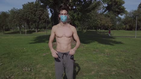 joven deportivo poniendo una máscara en su cara en el parque