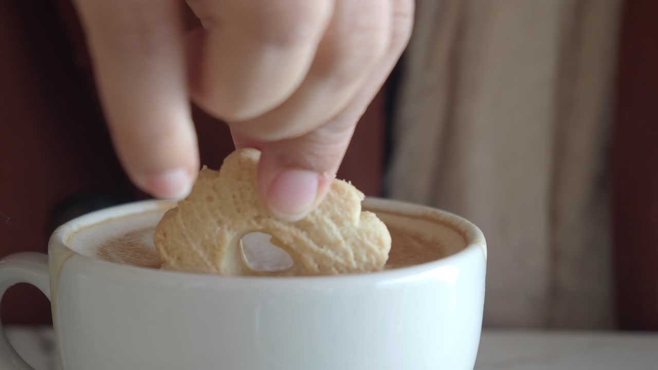 galleta sumergida en una taza de capuchino