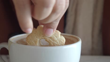 cookie dipped in a cup of cappuccino