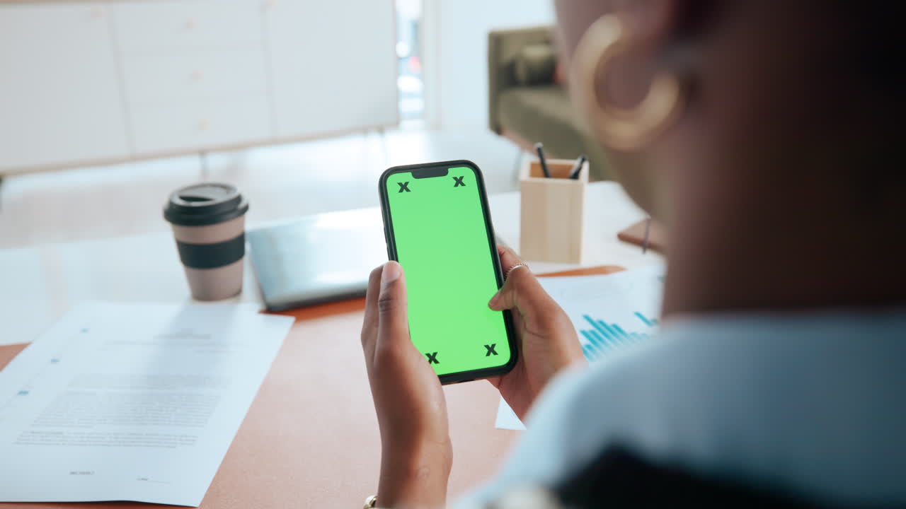 Woman using phone with green screen at desk
