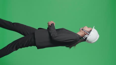side view of smiling asian female engineer talking while walking in the green screen studio
