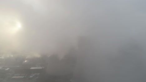 Aerial-reveal-view-of-UK-power-station-cooling-towers-through-smoke-steam-emissions-during-sunrise