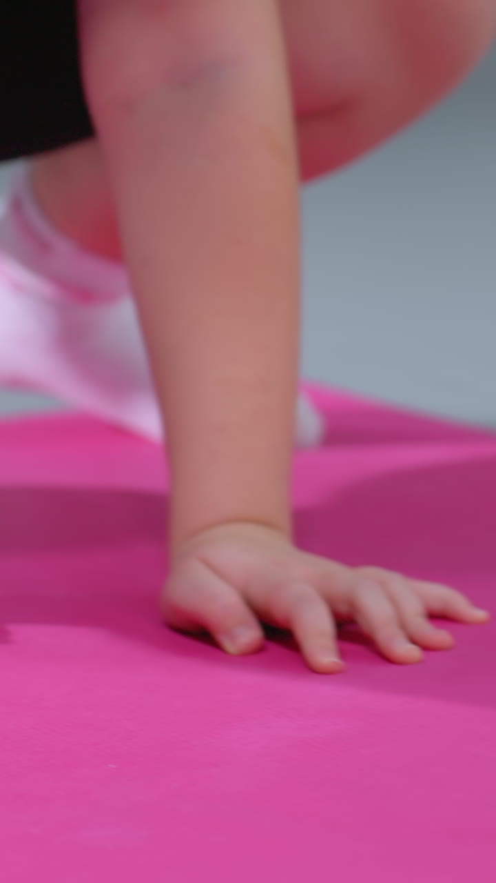 vista parcial de primer plano de una persona moviéndose hacia atrás mientras está de pie en una alfombra de yoga rosa con calcetines, participando en una sesión de entrenamiento enfocada con alfombras de ejercicio y accesorios de fitness en el fondo