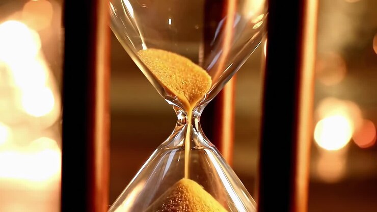 Close-up video of an hourglass with golden sand, captured at eye level, evoking time's passage