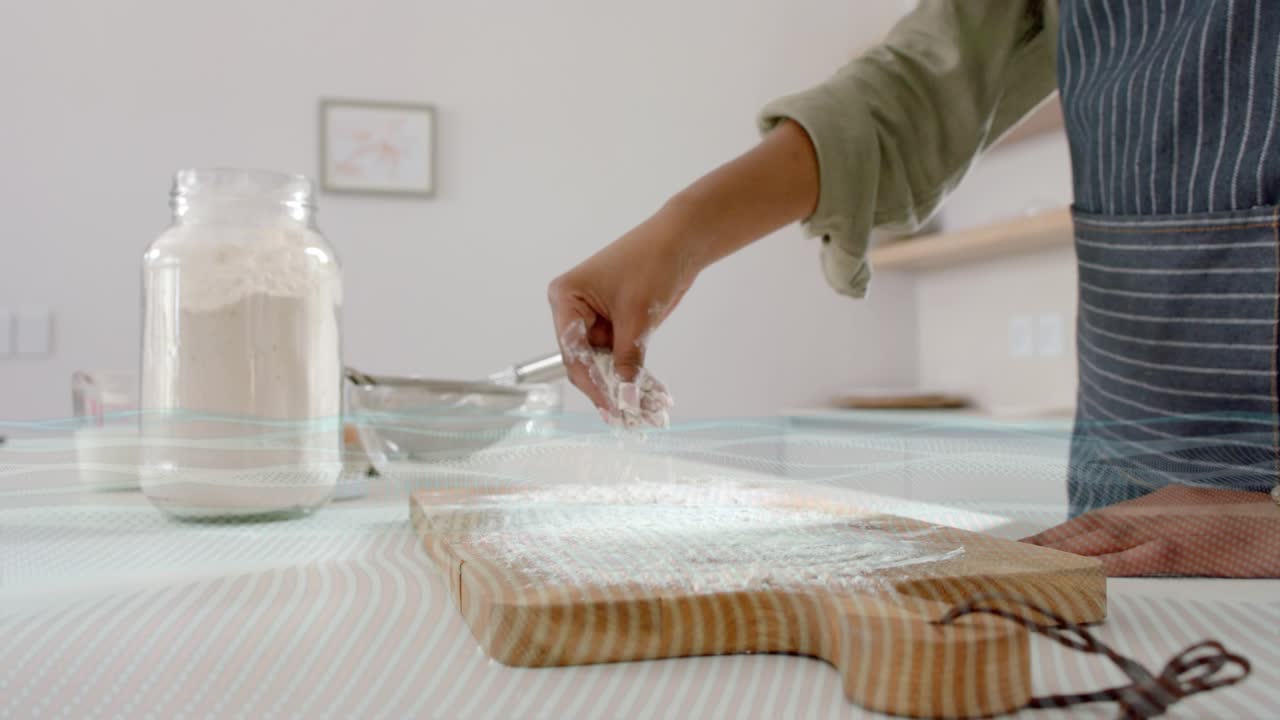 Cook reaching for flour jar, scooping and sprinkling flour on cutting board for baking