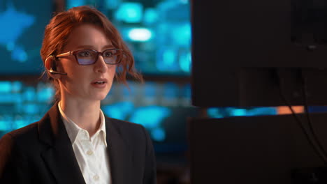 pan lento, una mujer de negocios en el trabajo hablando a través de sus auriculares bluetooth, en una industria de tipo servicio al cliente, expresión neutral