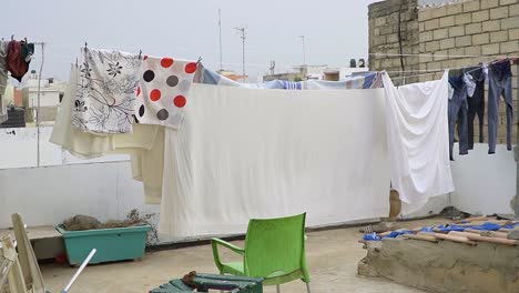 Clothes-and-bed-sheets-sun-drying-on-the-roof-terras-in-Dakar,-Senegal