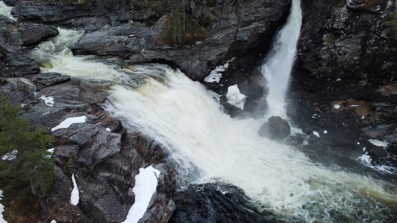 Panorering fra venstre til høyre avslører en foss som fosser gjennom en snødekt skog i de norske fjellene