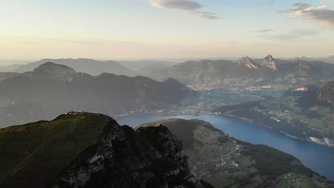 vuelo aéreo alrededor de la cumbre de niederbauen chulm en una tarde dorada de verano en los alpes suizos con vistas a mythen, rigi, burgenstock, pilatus y acantilados resplandecientes sobre el lago lucerna