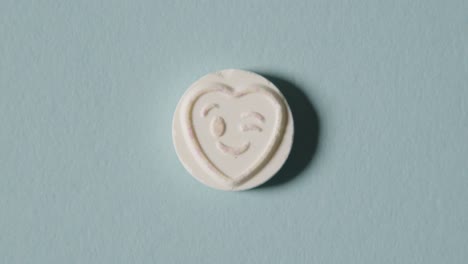 caramelo de corazón con emoji guiñando un ojo sobre fondo azul