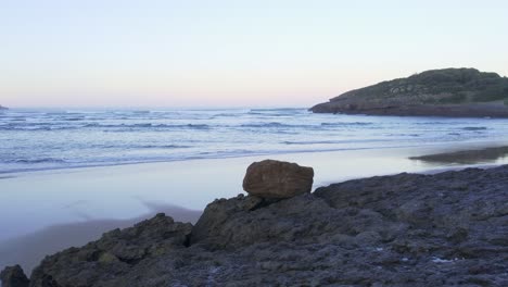 Niedrige-4K-Luftaufnahme-über-Felsen-Zeigt-Leere,-Idyllische-Meereslandschaft,-Sonnenuntergangsstrand,-Spanien